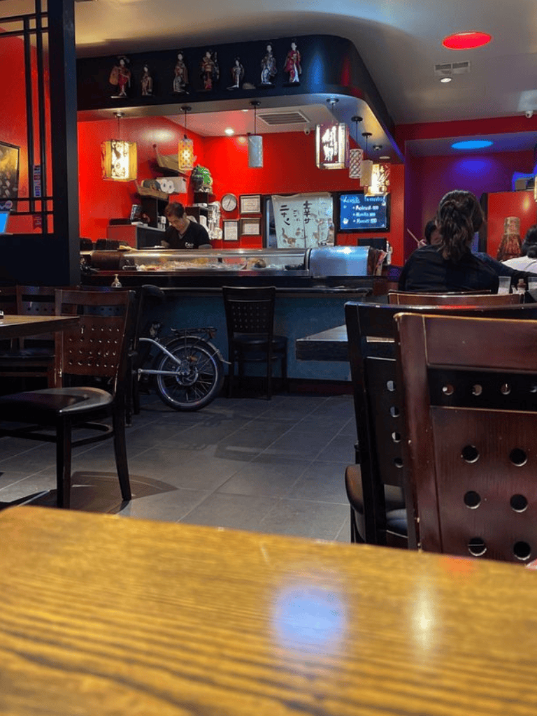 Colorful Asian restaurant interior with sushi bar and patrons dining.