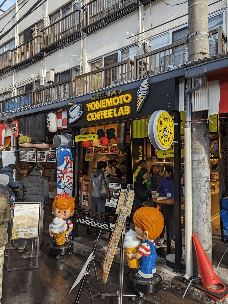 Yonemoto Coffeelab exterior with cartoon character statues and busy street scene near QuestForDirections.