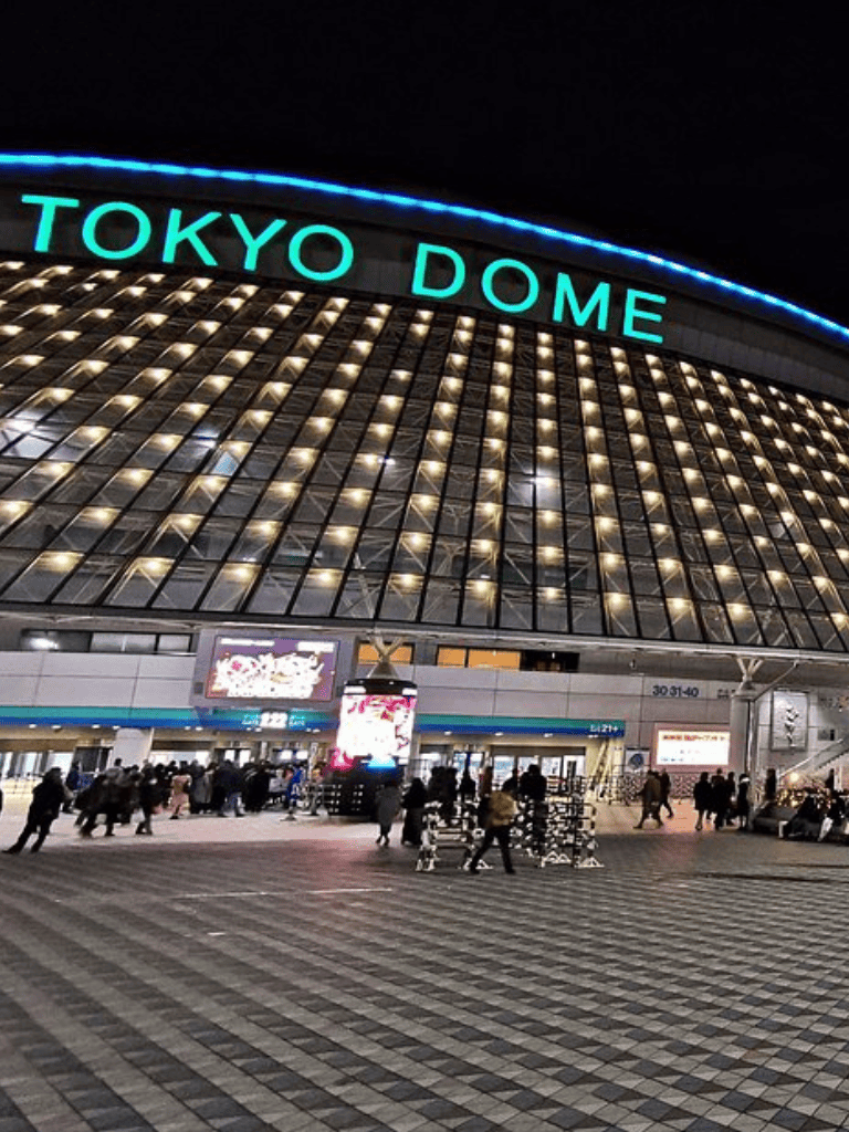 Brightly lit Tokyo Dome at night with visitors entering the venue.