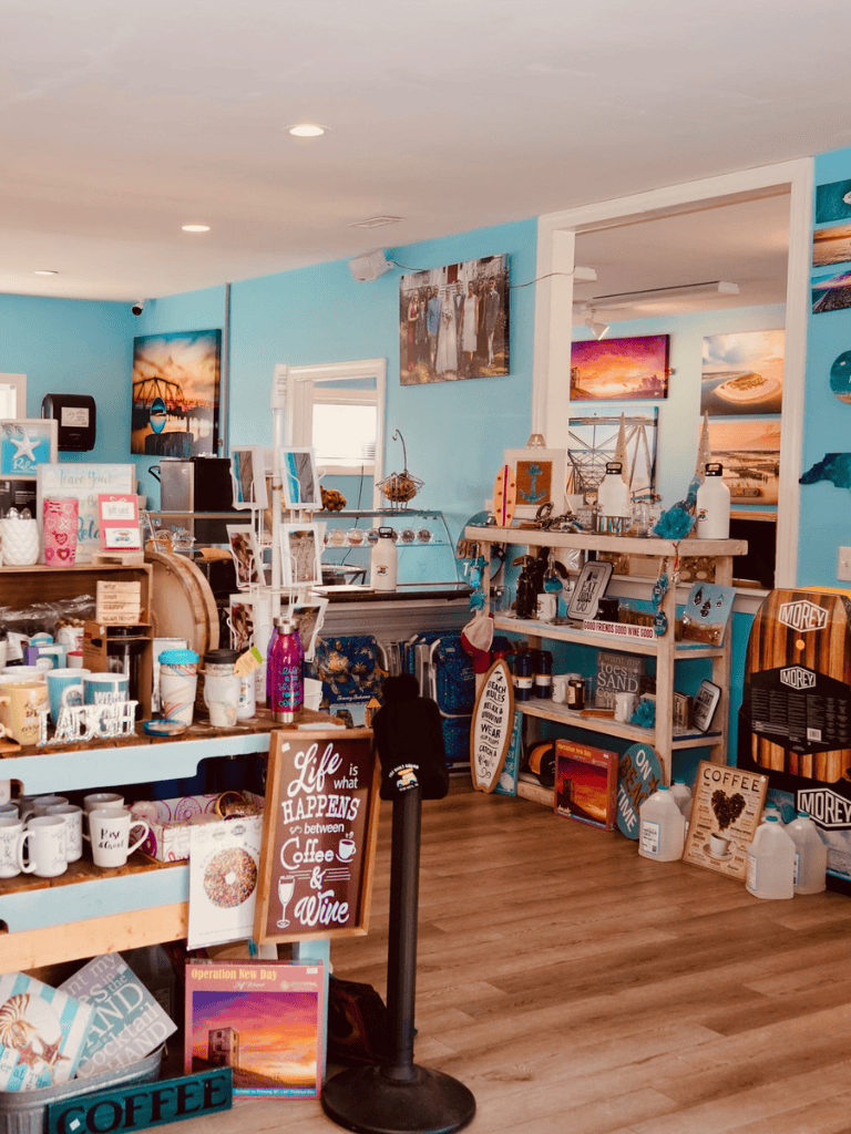 Colorful coastal-themed souvenir shop interior with beach decor and framed ocean photography.