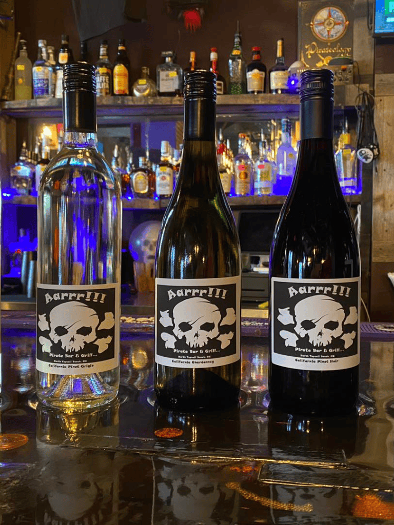Aarr!!! Pirate-themed wine bottles at a bar with liquor bottles in the background.