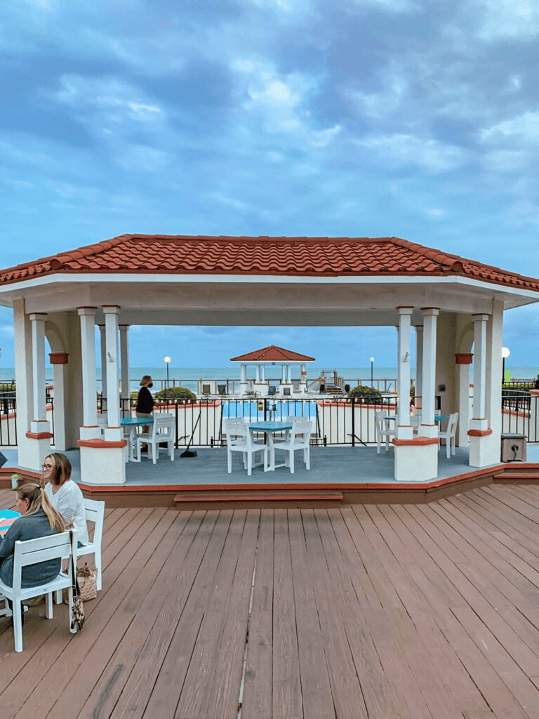 Relaxing seaside pool area with gazebo and ocean view, perfect for vacation and family fun.