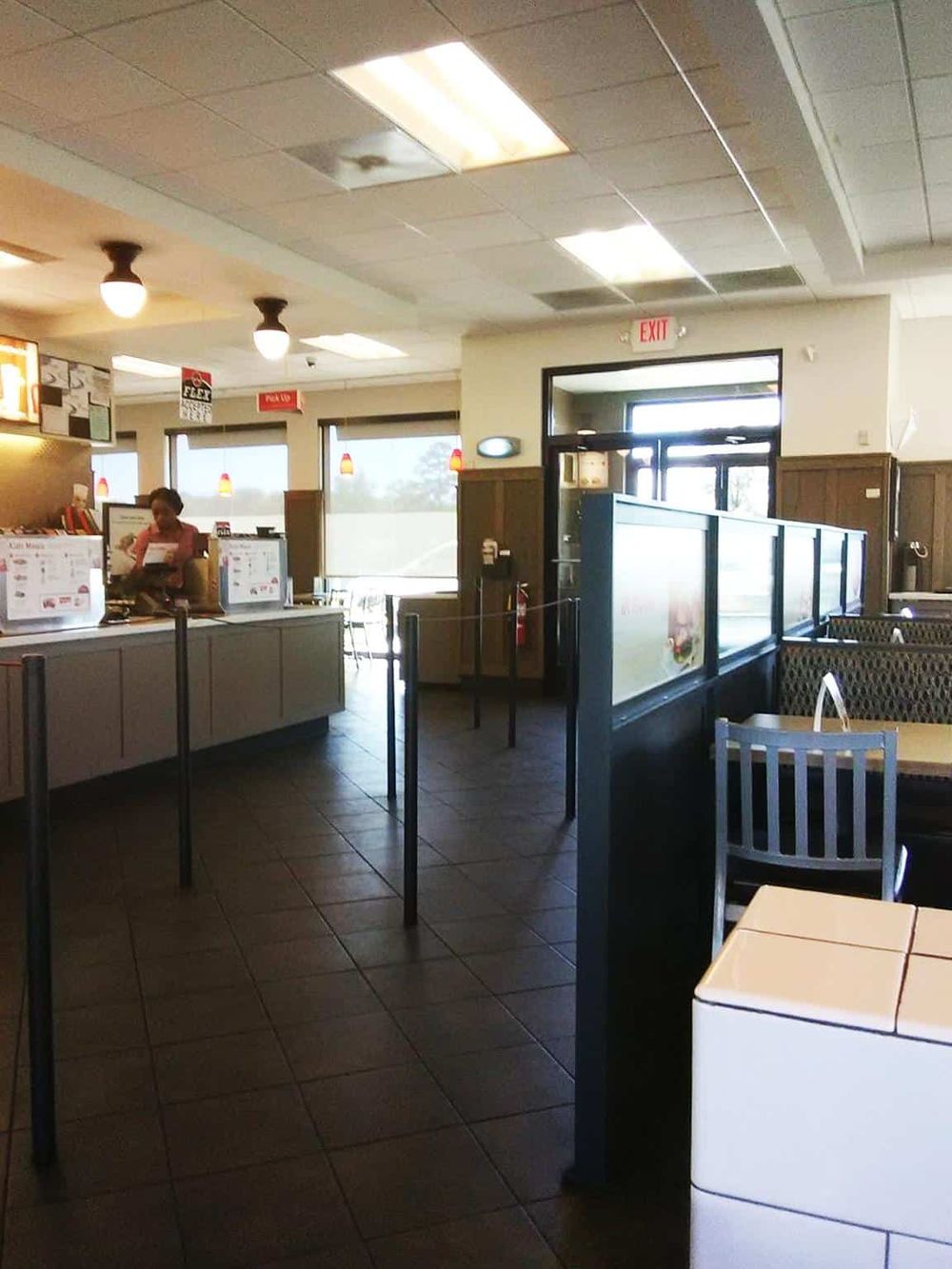 Orderly fast food restaurant interior with a counter, seating area, and customer ordering.