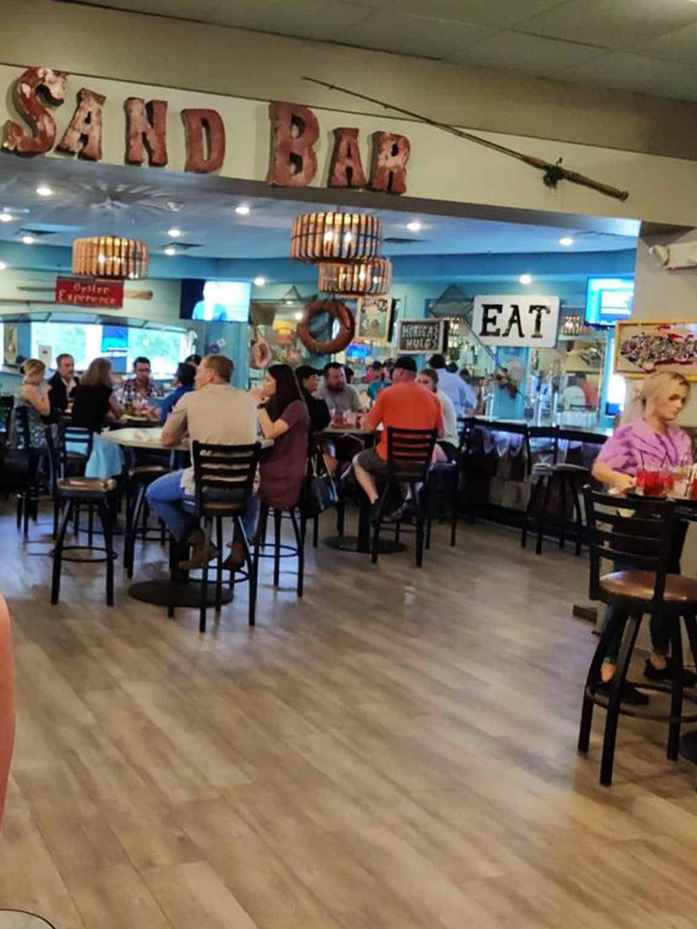 Outdoor bar and dining area at a seafood restaurant with nautical decor and a lively atmosphere.