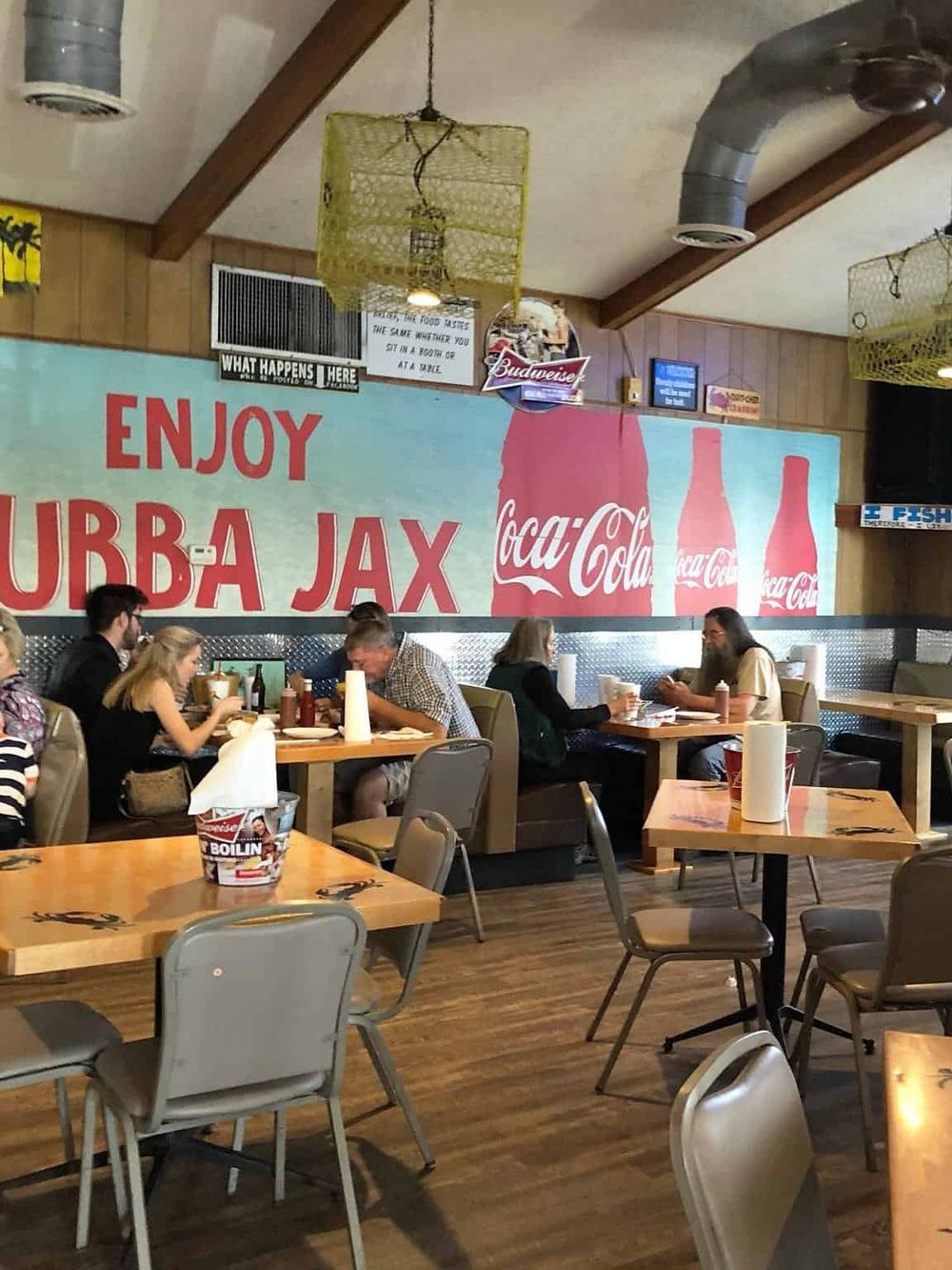 Casual restaurant interior with diners dining, Coca-Cola mural, and cozy ambiance.