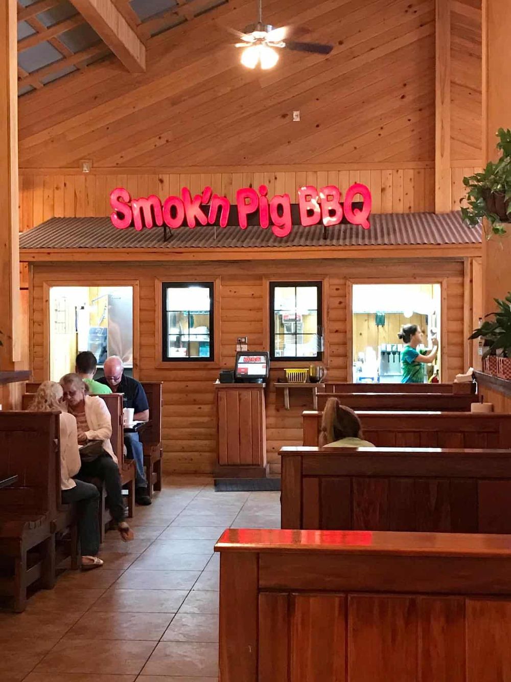 Smokin Pig BBQ restaurant interior with wooden decor and diners enjoying their meal.