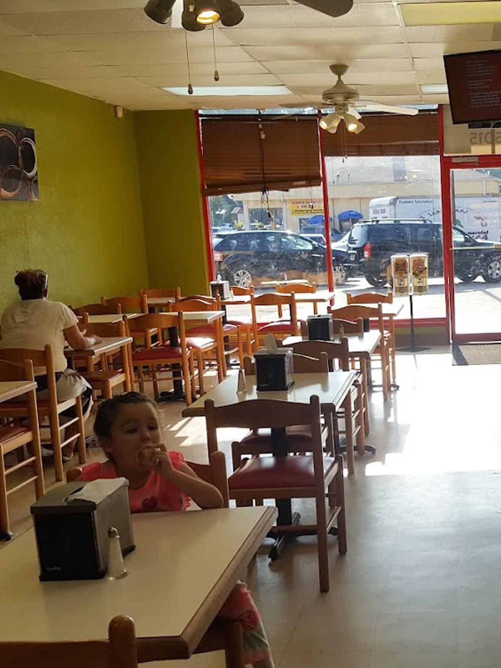 Cozy family-friendly restaurant interior with wooden tables, large windows, and kids enjoying a meal.