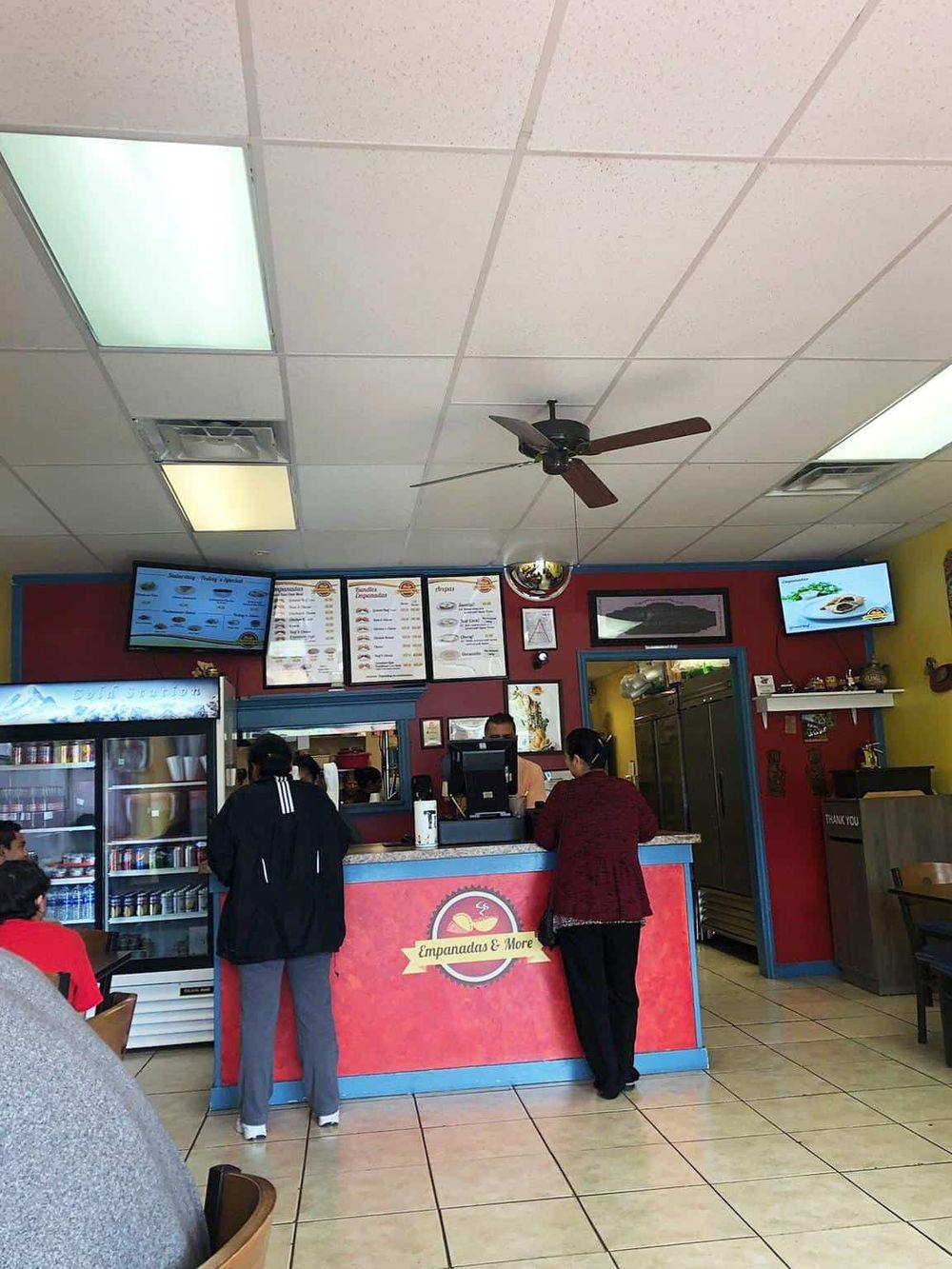 Freshly made empanadas and quick service at a casual restaurant counter inside a vibrant eatery.