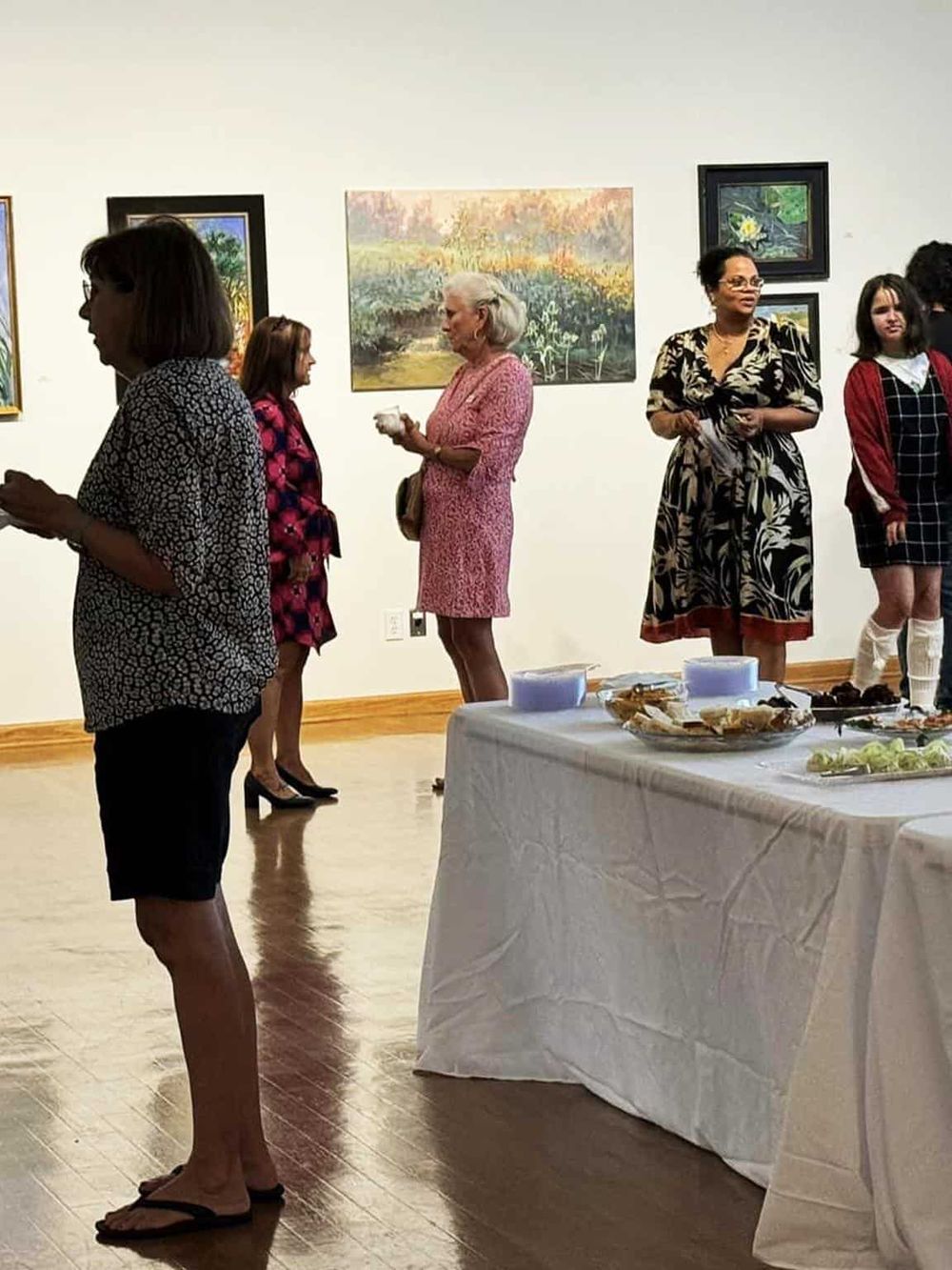 Elegant art gallery exhibition showcasing diverse artwork and guests networking at QuestForDirections event.