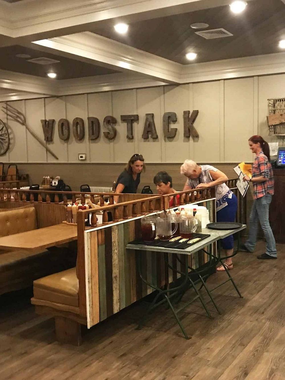 Cozy restaurant interior at Woodstock with people ordering food, rustic decor, and warm lighting.