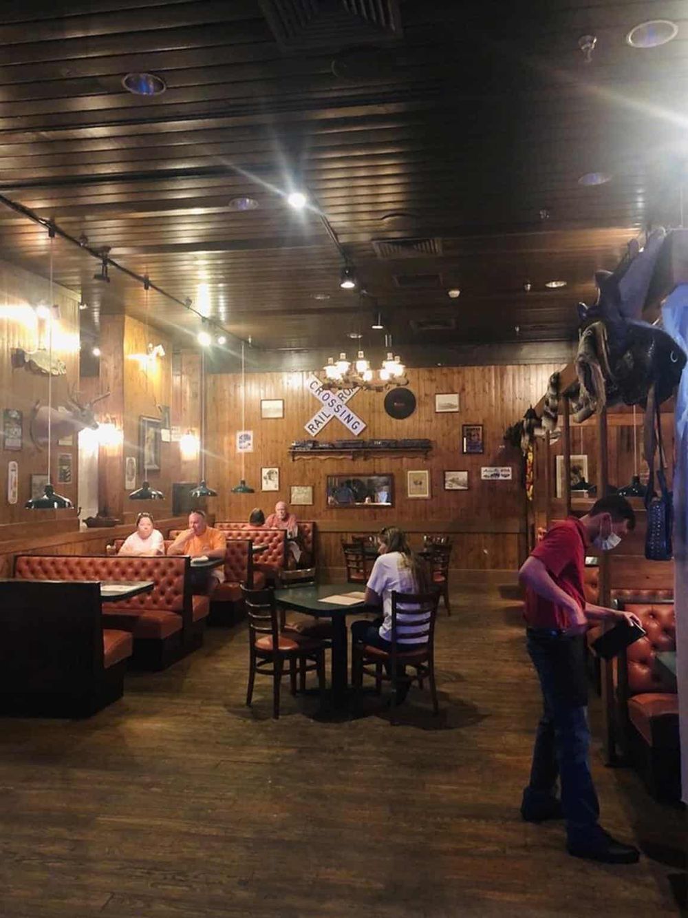 Cozy rustic restaurant interior with wooden walls, vintage decor, and patrons dining comfortably.