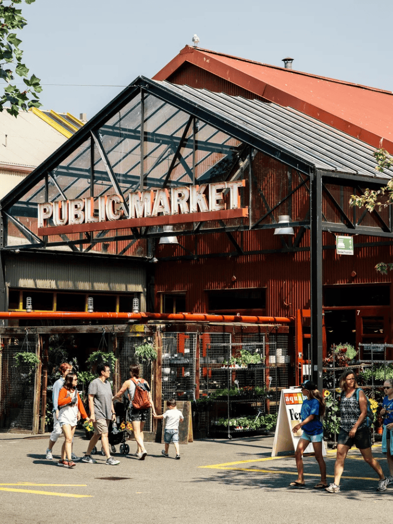 Fresh produce vendors at a vibrant public market with shoppers.