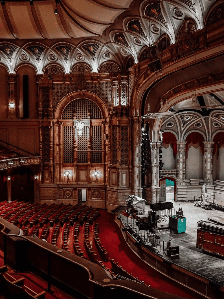 Elegant historic theater interior with ornate woodwork and stage setup for performances.