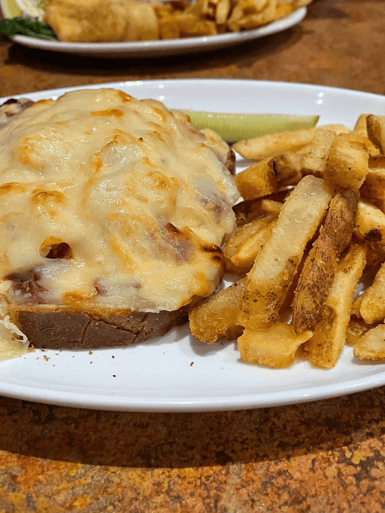 Cheesy baked potato with fries on white plate, delicious comfort food, Quest for Directions restaurant image.