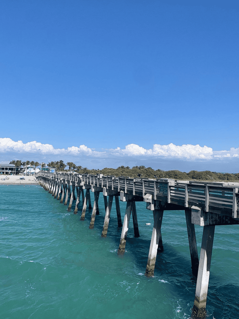 Seaside pier extending over turquoise ocean waters under a blue sky.