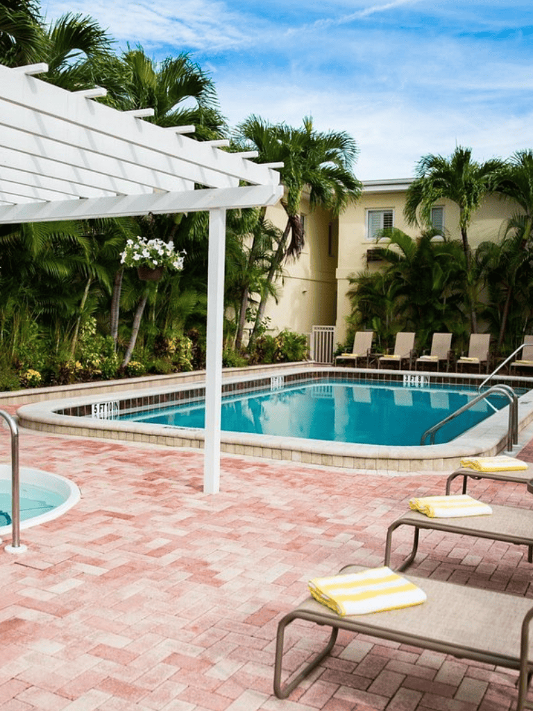 Relaxing hotel pool with lush tropical palm trees and comfortable lounge chairs, perfect for vacation at Quest For Directions.