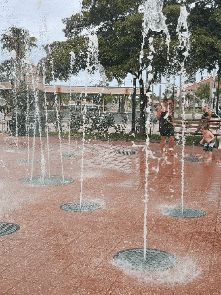 Spray water fountains in a park, children playing, outdoor recreational activities, urban splash pad, family fun at QuestForDirections.