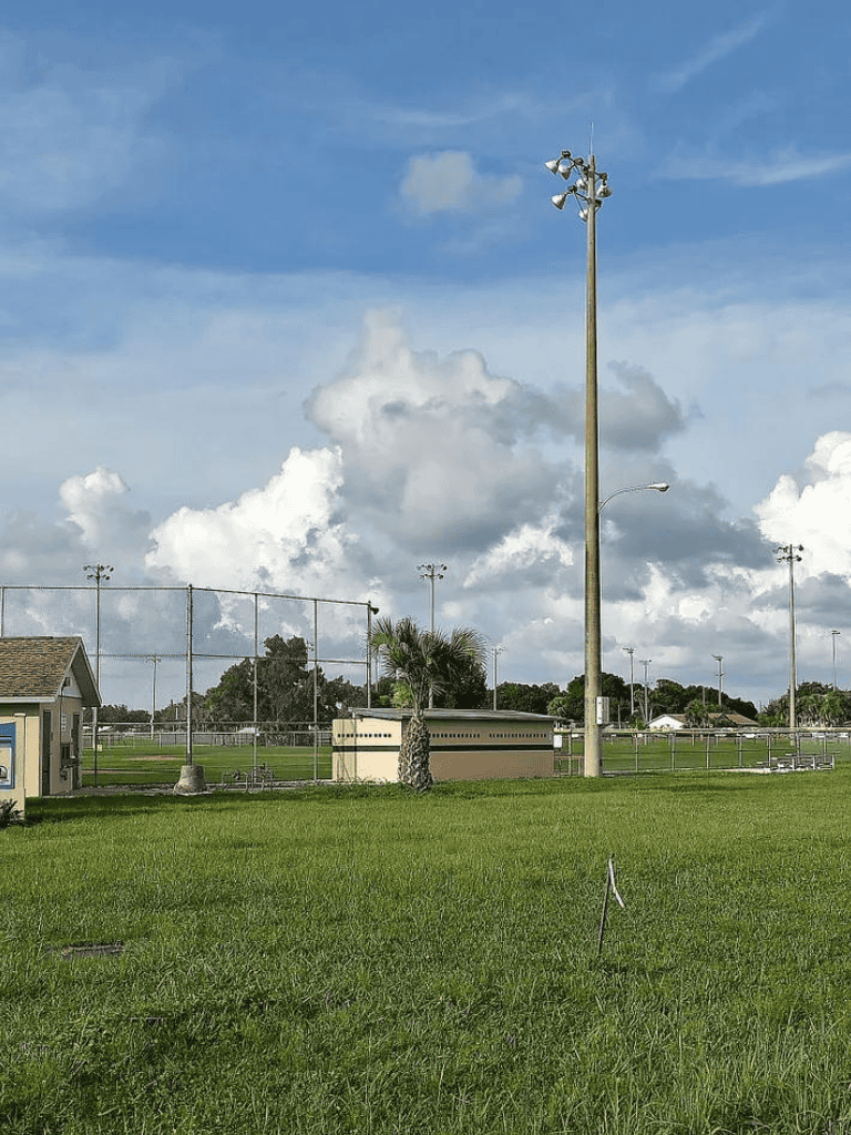 Tall outdoor sports field lighting and chain-link fencing at a community baseball field.