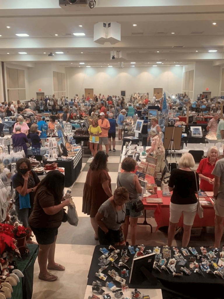 Colorful indoor craft and gift market bustling with shoppers and vendors at QuestForDirections event.