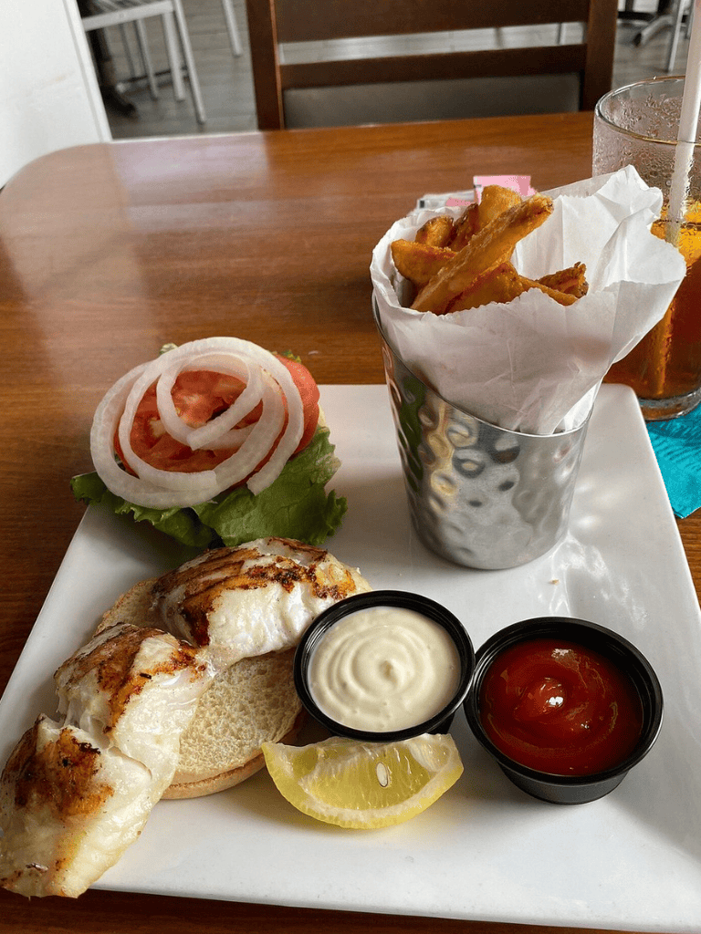 Crispy fish sandwich with fresh vegetables, fries, and dipping sauces served at QuestForDirections restaurant.