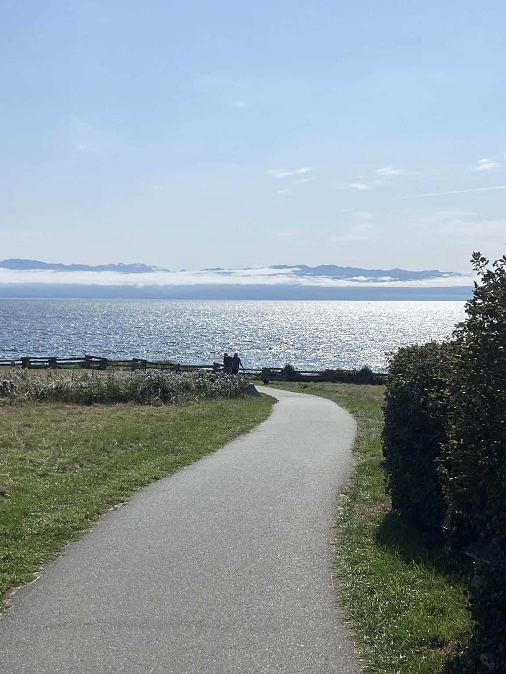 Serene coastal walking trail with ocean views and a couple enjoying the scenery. Perfect for outdoor adventure and nature exploration.