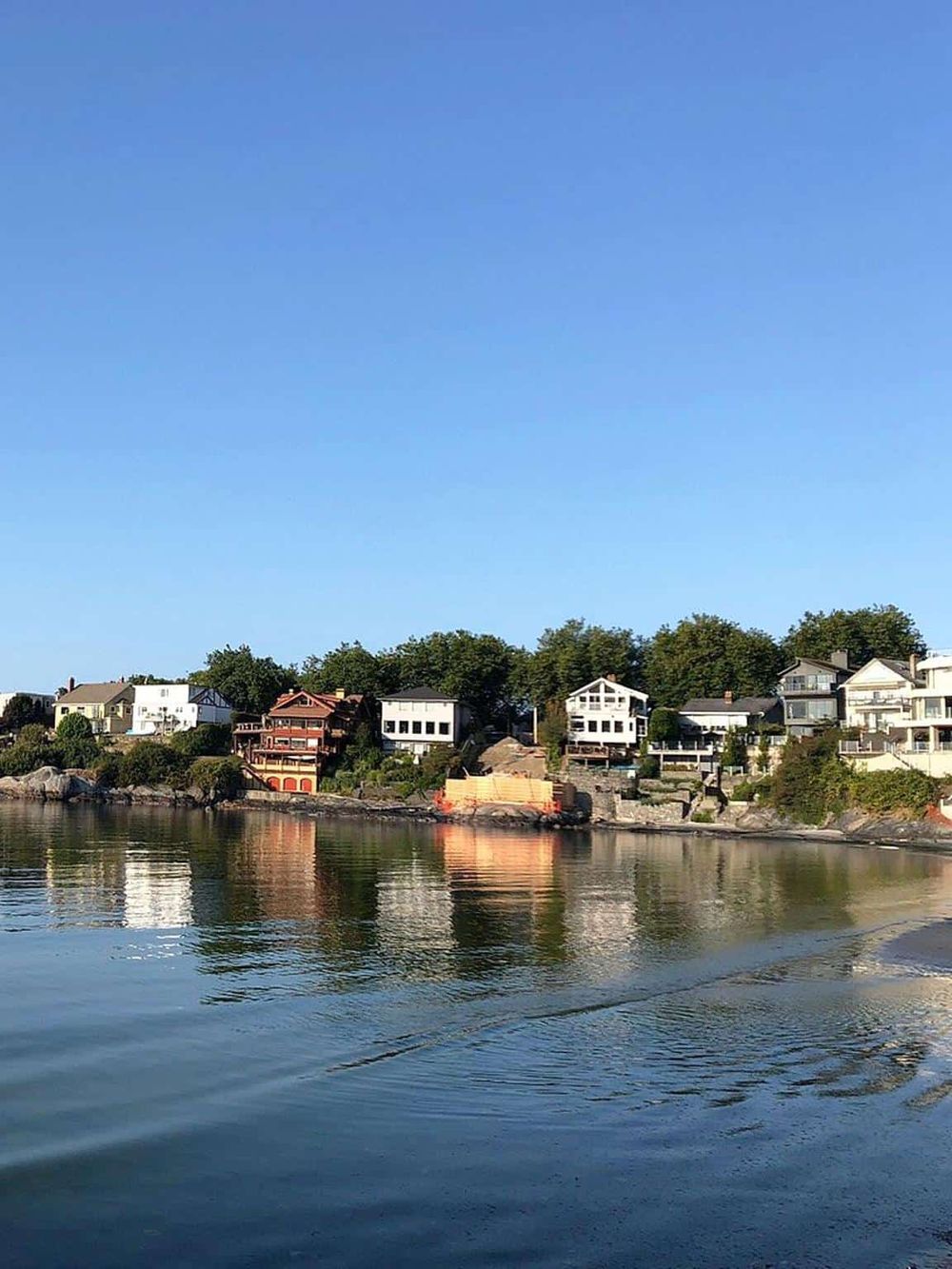 Picturesque waterfront neighborhood with modern homes along a calm river under a clear blue sky.