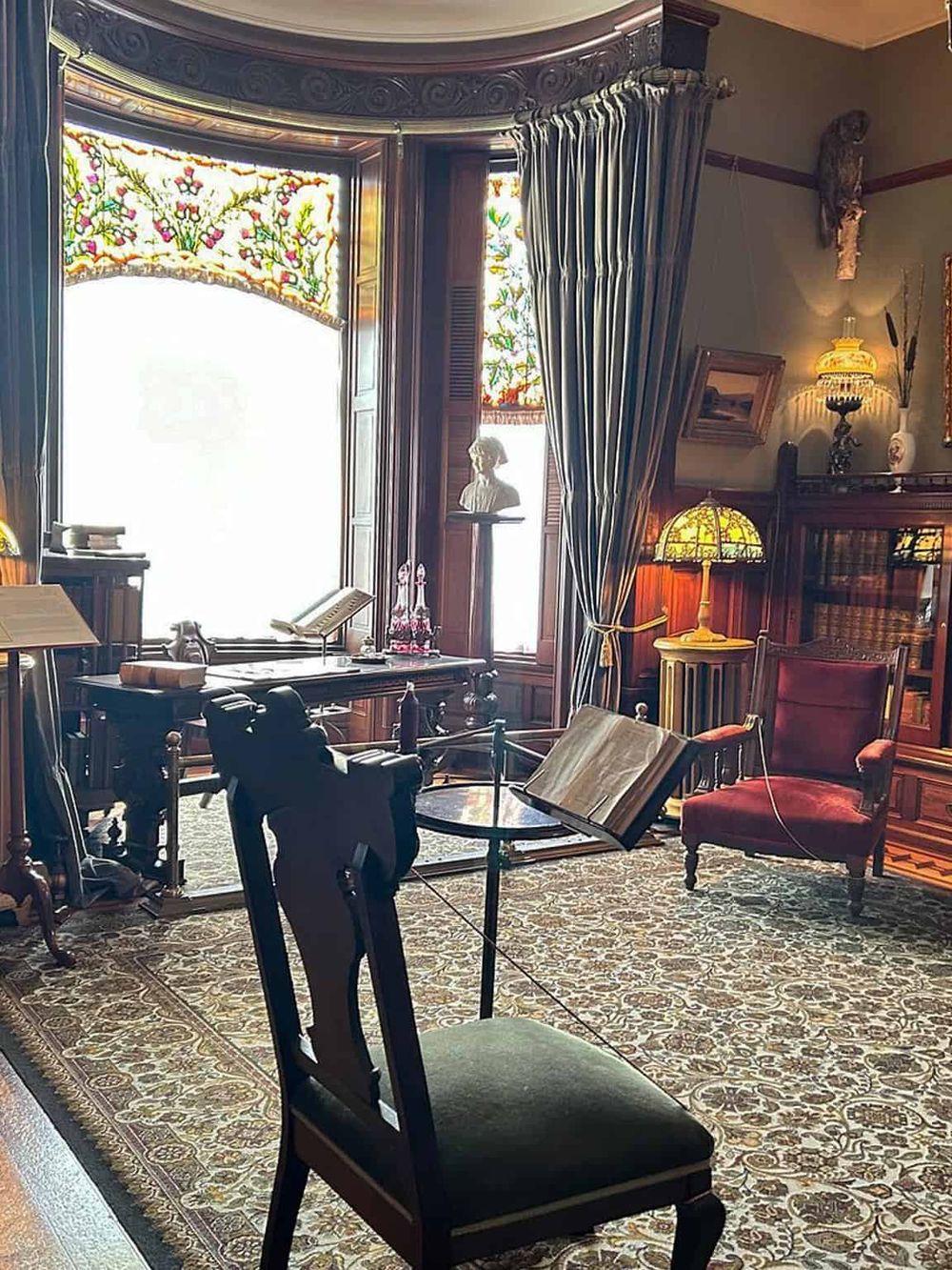 Intricate antique-style living room with vintage furniture and stained glass windows, perfect for book lovers and history enthusiasts.