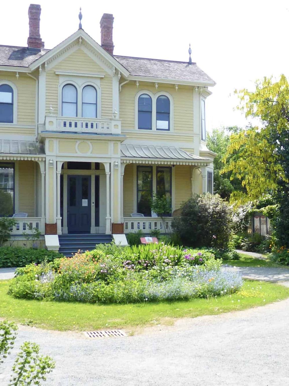 Charming Victorian house with lush garden and vibrant flowers, perfect for exploring local architecture and garden design.