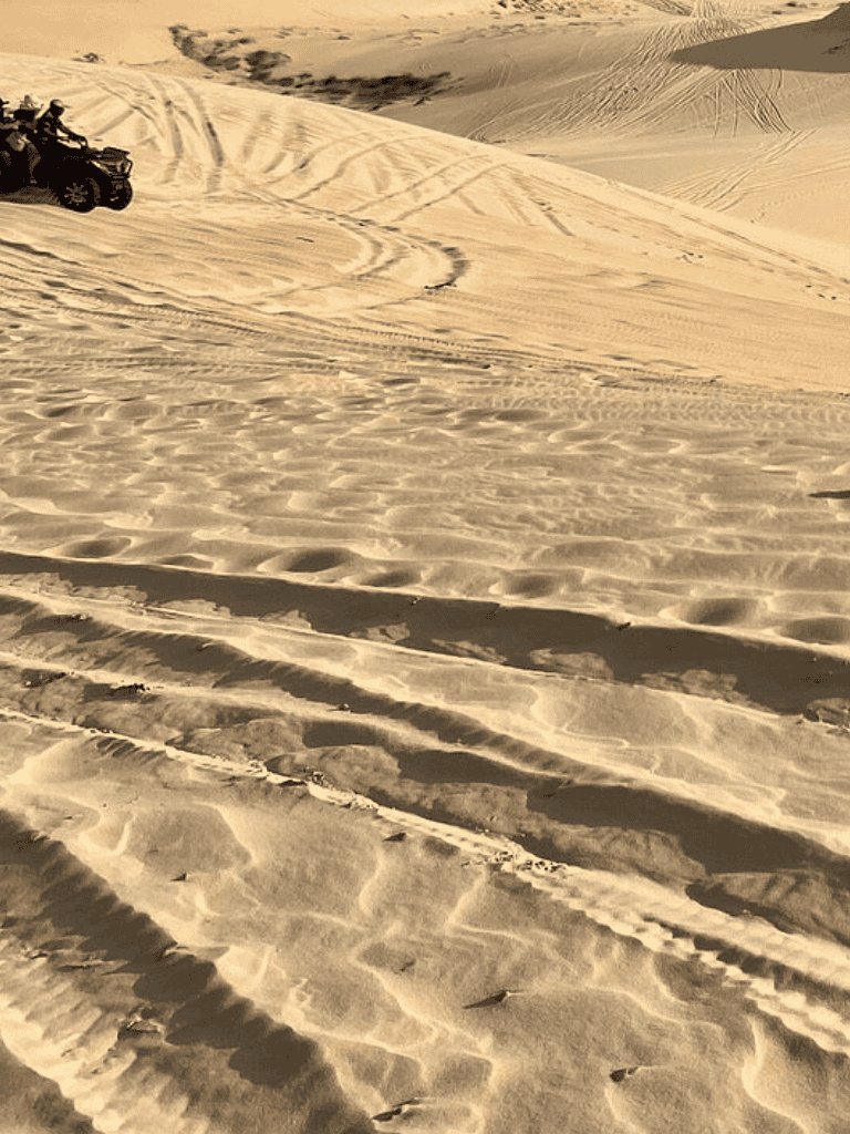 Off-road vehicle driving through desert sand dunes, adventure, exploration, and travel in sandy landscape.