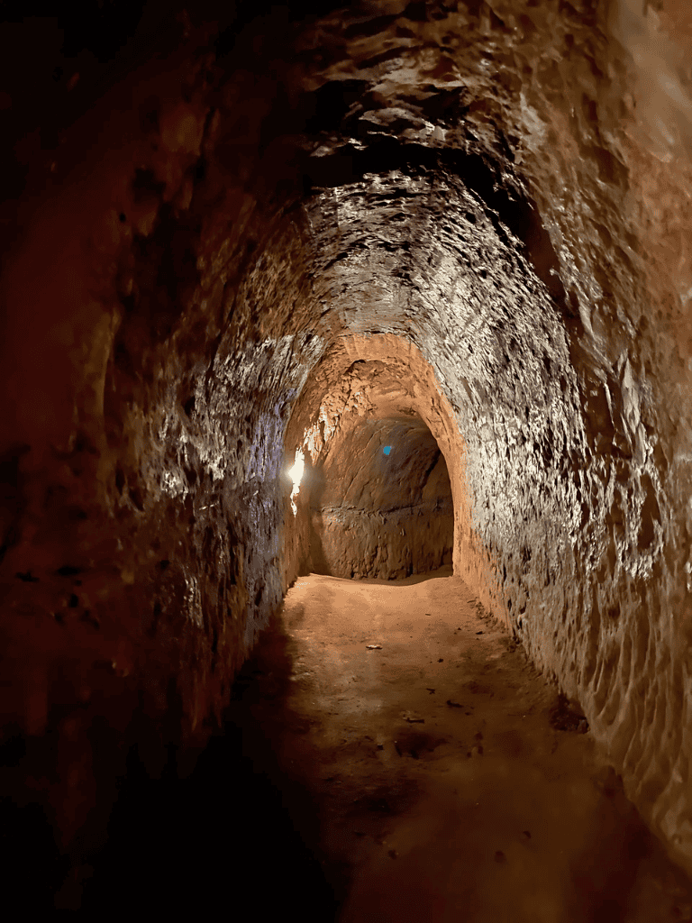 Ancient underground tunnel carved from rock, part of QuestForDirections historic site.