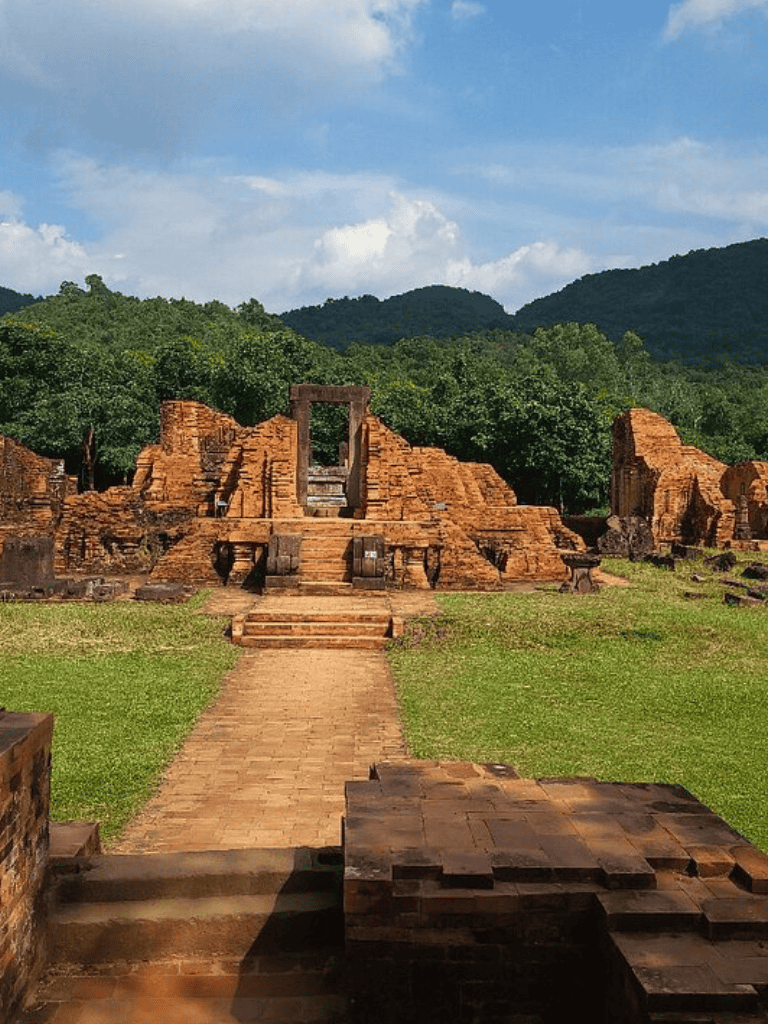 Ancient temple ruins with lush green mountains in the background, showcasing historic architecture and scenic nature views.