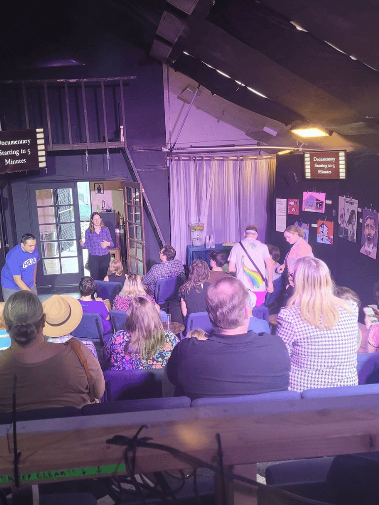 Auntie, "QuestForDirections" documentary film screening with audience, speaker, and artwork in the theater.