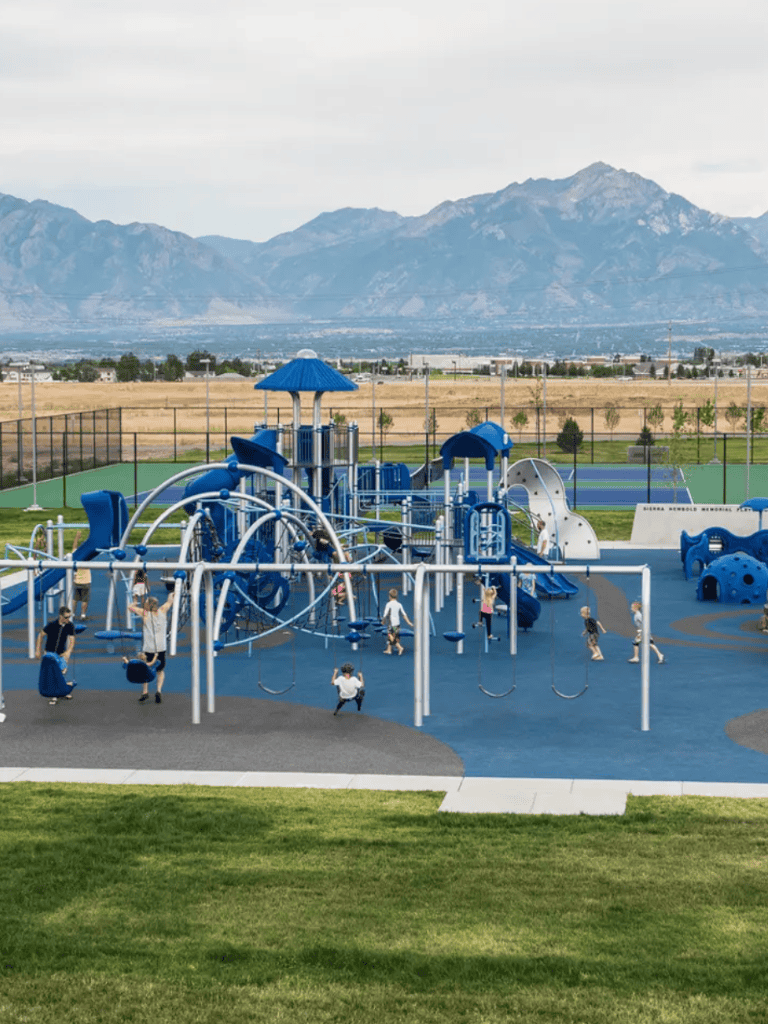 Colorful playground equipment with kids playing, mountain view in the background, ideal for community recreation and outdoor fun.
