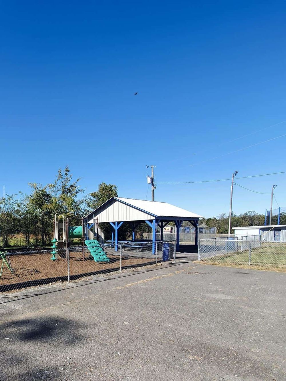 Playground with shade shelter and fenced area in outdoor school or park setting.