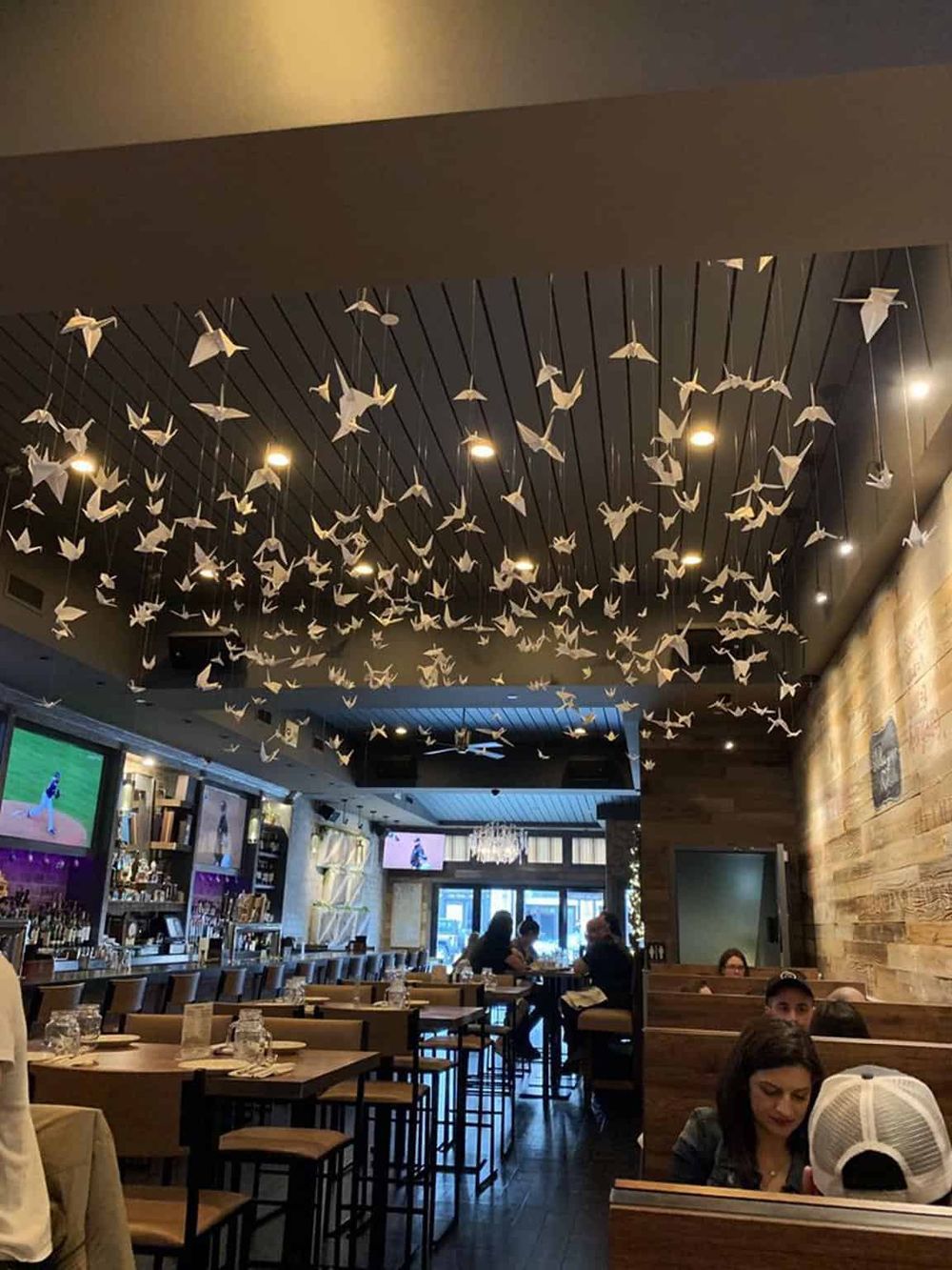 Origami crane ceiling installation in a modern restaurant interior for a unique dining experience.