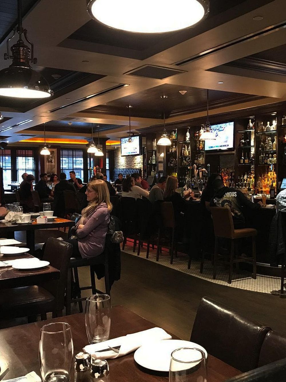 Cozy bar interior with patrons enjoying drinks at a bustling venue, perfect for socializing and entertainment.