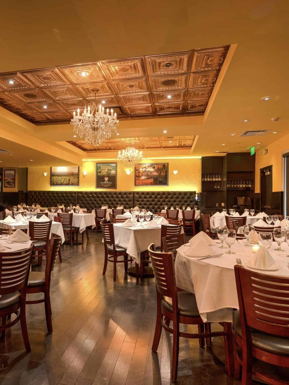 Upscale restaurant interior with elegant chandeliers, white tablecloths, and sophisticated decor.
