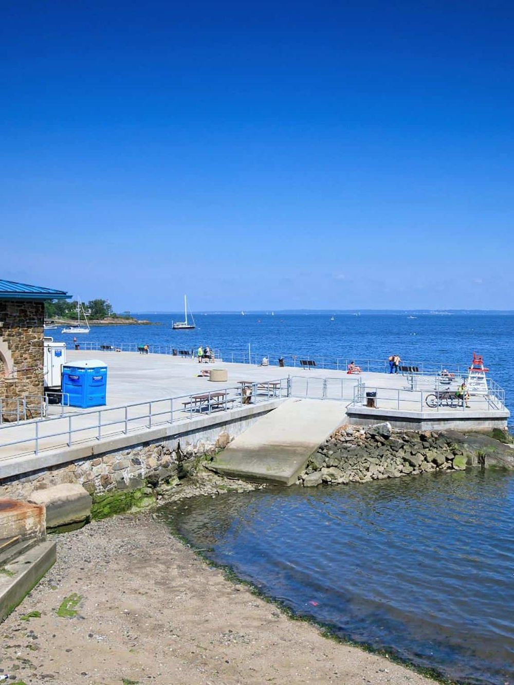 1. Coastal waterfront with boat docks, clear blue sky, and sandy shoreline for travel and outdoor adventures.