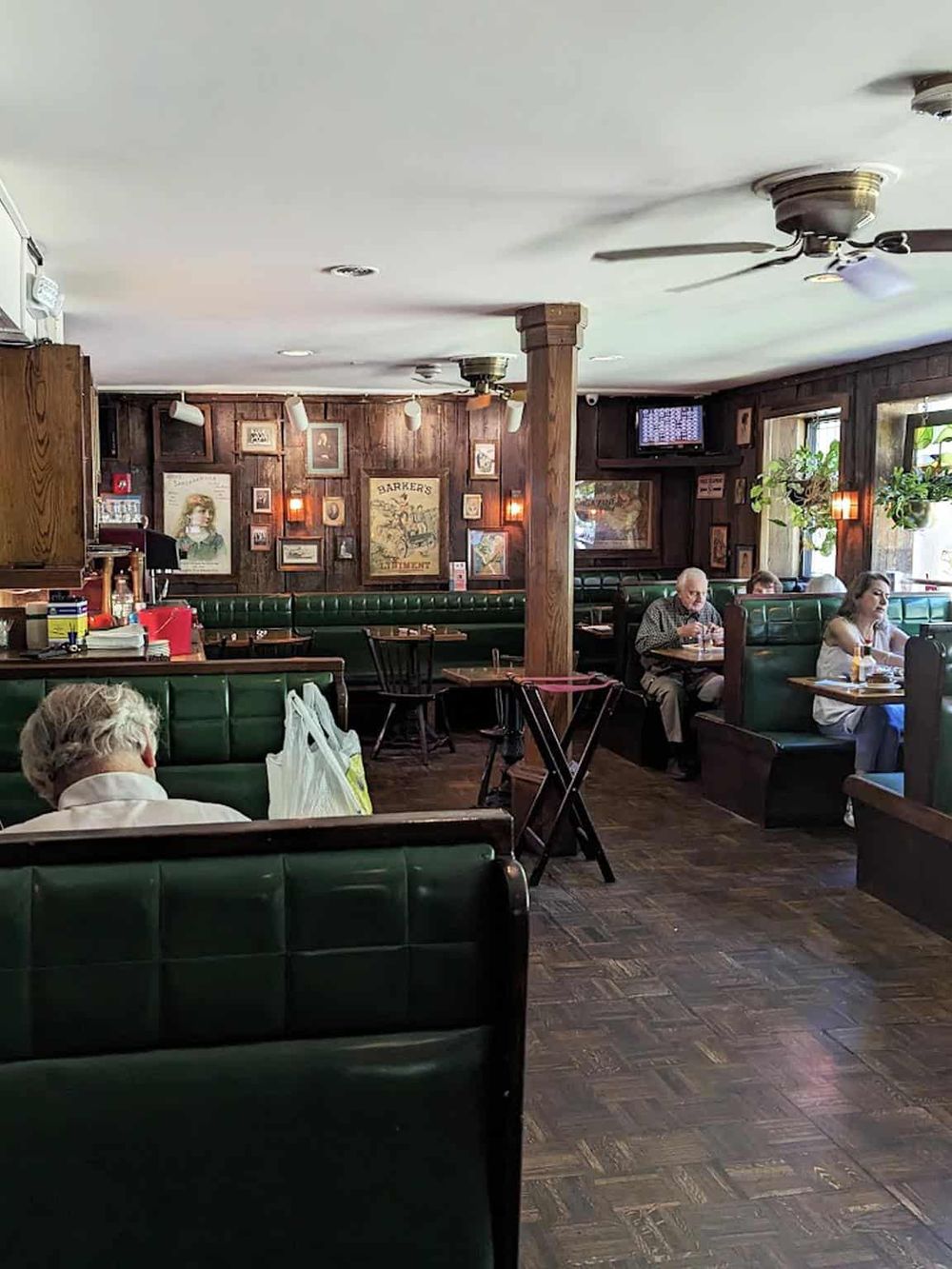 Cozy restaurant interior with green booths, wooden accents, and vintage decor for a welcoming dining experience.
