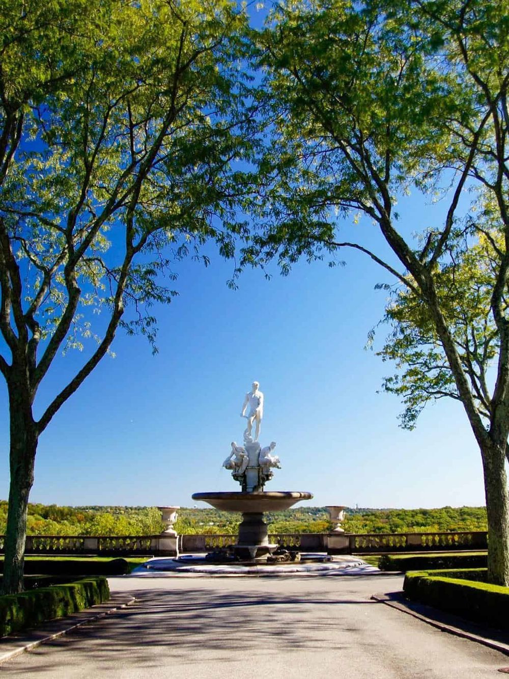 Serene outdoor park with classical sculpture fountain, lush green trees, and scenic views - perfect for relaxing and outdoor activities.