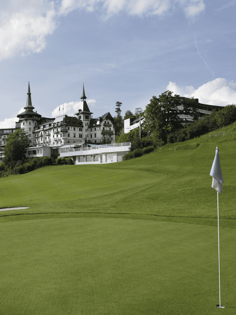Luxury castle hotel overlooking a golf course with a putting green and flagstick.