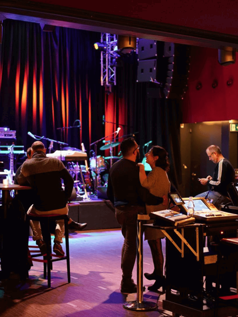Live music venue with stage and audience, vibrant lighting, and intimate setting.