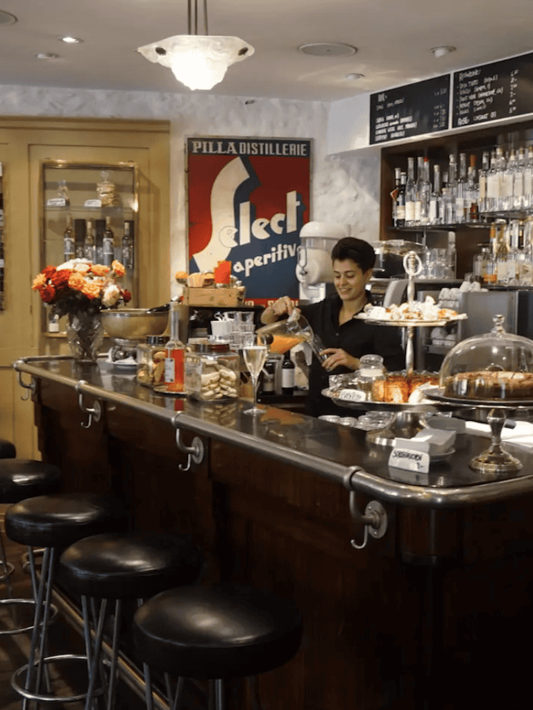 Relaxed bar scene with a smiling bartender and cocktail ingredients in a stylish cafe setting.