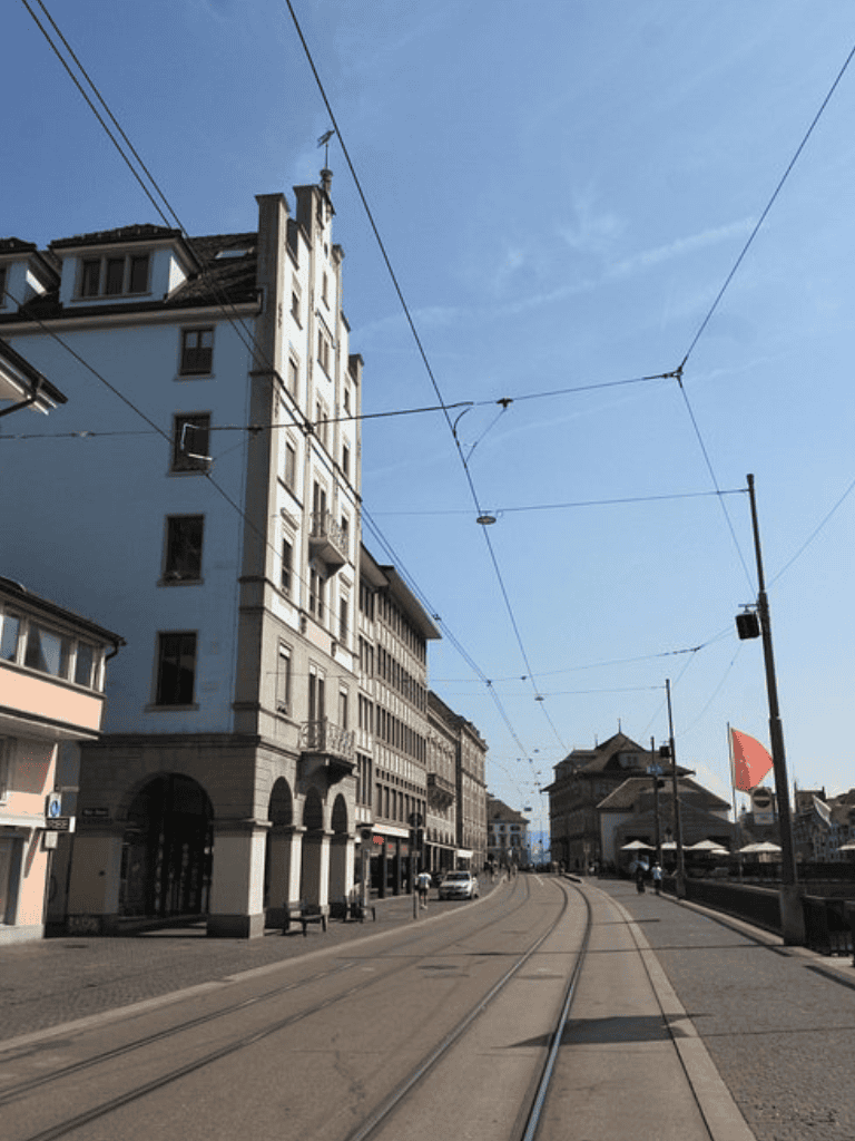 Modern city street with tram tracks and historic buildings in Zurich, Switzerland.