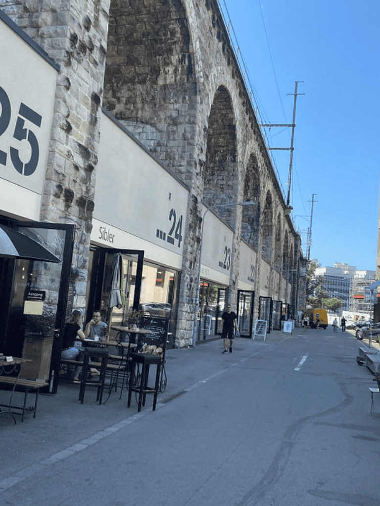 Outdoor dining area under historic stone arches, modern cafes along questfordirections.com.