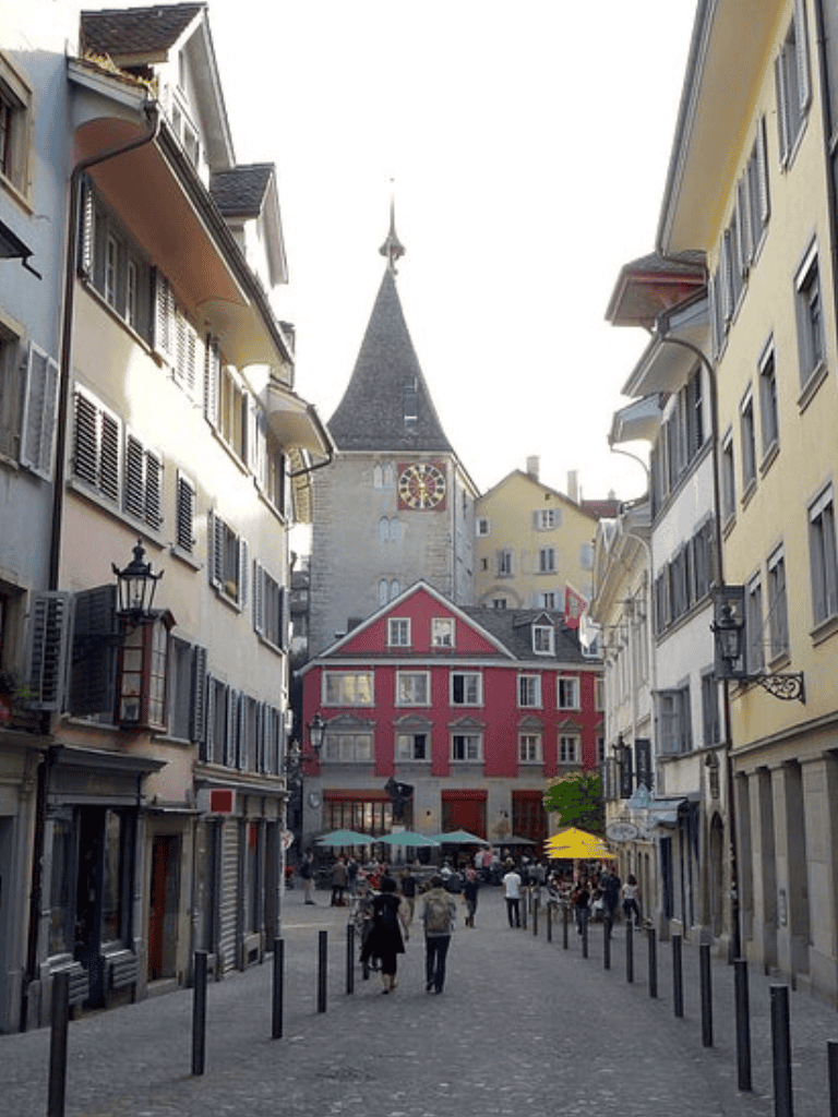 Charming European city street with historic architecture and bustling cafe scene, perfect for guided tours.
