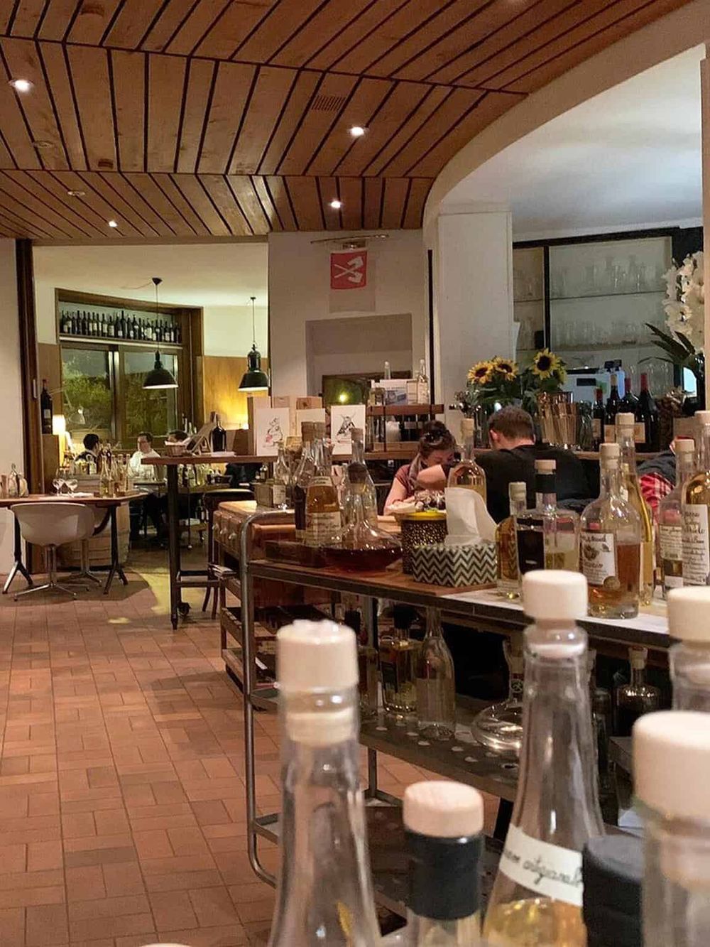 Elegant restaurant interior with bartop, wine bottles, and stylish lighting, showcasing a welcoming dining environment.