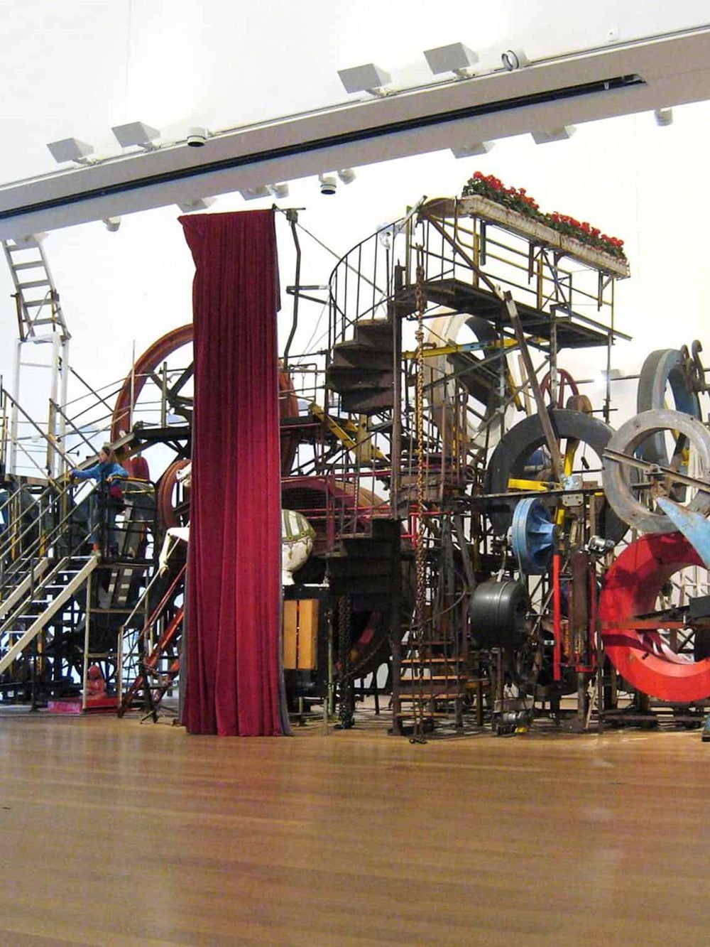 Innovative theatrical stage design with mechanical elements and vibrant red curtains.