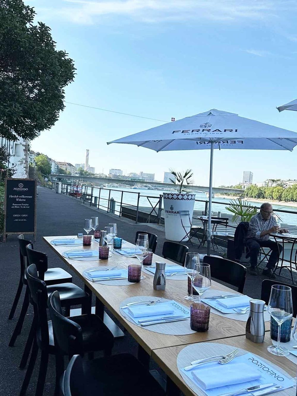Outdoor riverfront dining at Ferrari restaurant with a scenic view and elegant table settings.