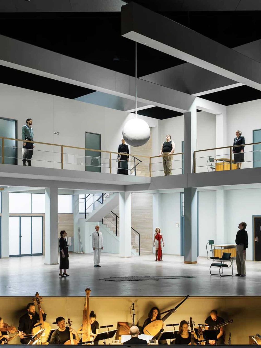 Modern multi-level office space with people socializing and musicians performing on stage.